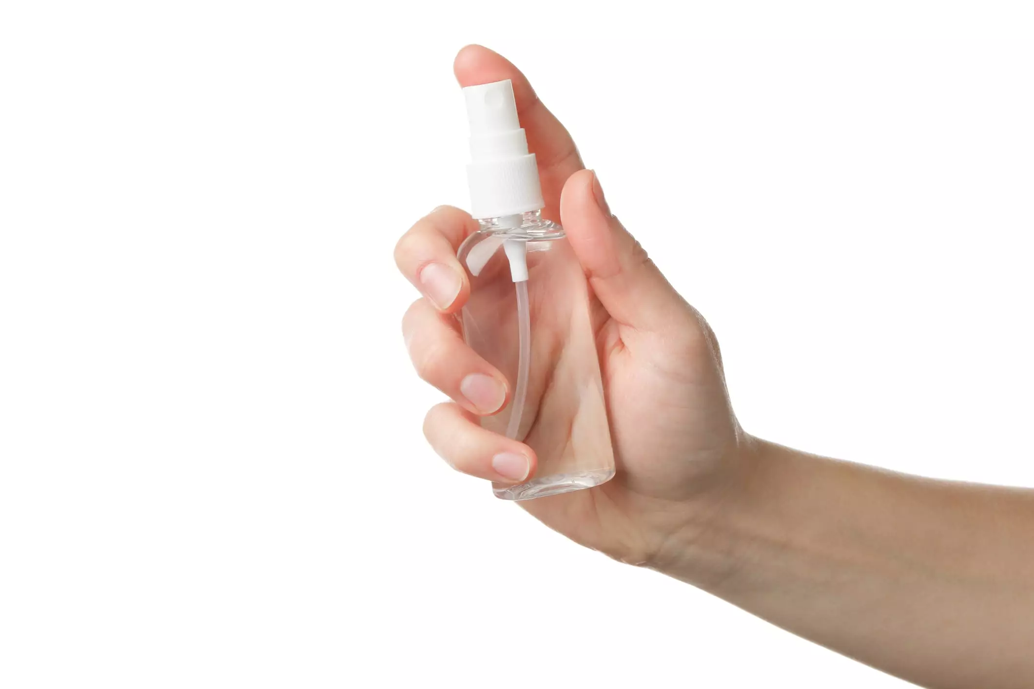 A hand holding a small, transparent spray bottle with a white nozzle, set against a plain white background.
