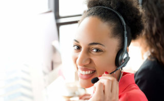 Smiling black businesswoman working in call center Contact Us
