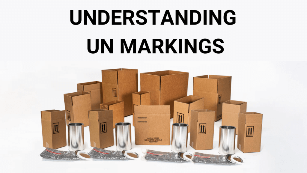 UNDERSTANDING UN MARKINGS A group of various sizes of brown cardboard boxes, some open and some closed, arranged in front of shiny metal containers and sealed plastic bags. The text above reads "UNDERSTANDING UN PACKAGING MARKINGS.